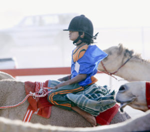 child racing a camel in UAE