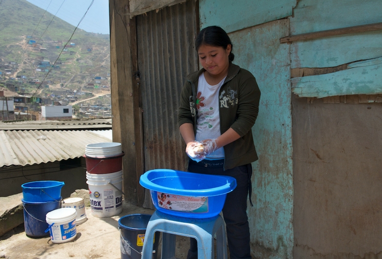 A child domestic worker washes up outdoors in Peru