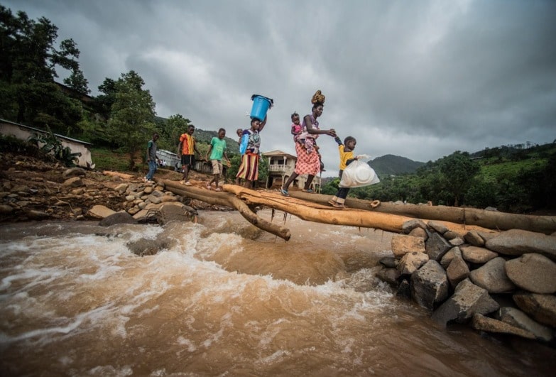 Women cross a gushing river