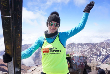 A fundraiser poses on top of a mountain