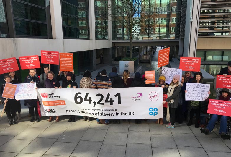 Survivors of slavery outside Home Office, their backs to the camera