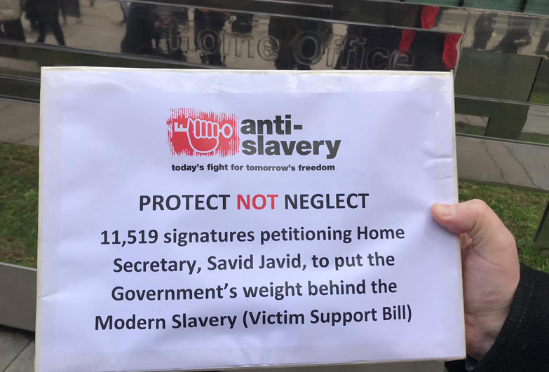 Holding protect not neglect sign outside UK Home Office