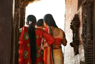 3 women stand with their backs to camera