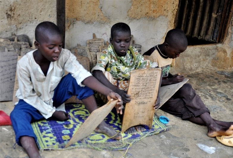 3 young boys study whilst sitting on the floor.
