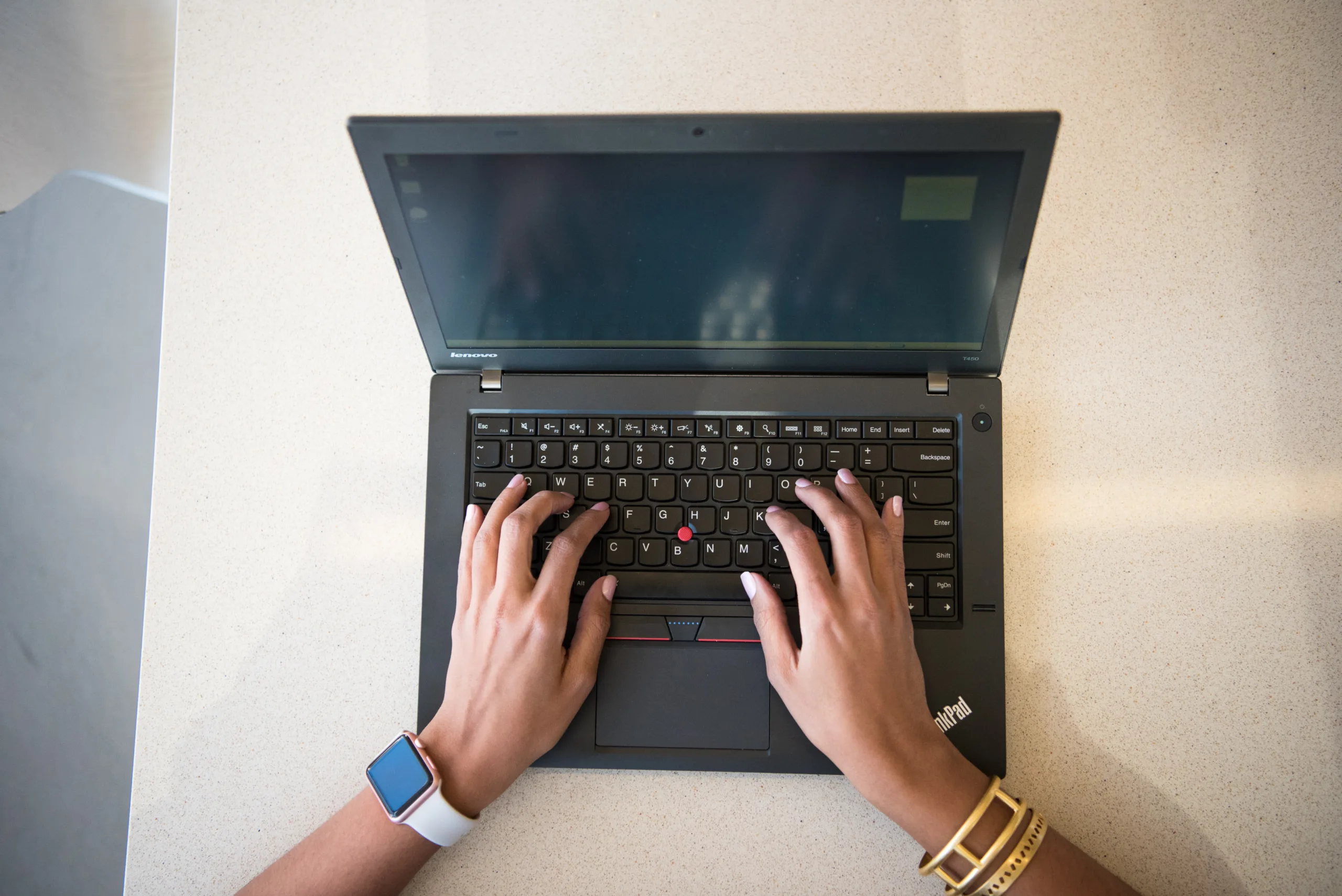 Hands typing on a laptop from above