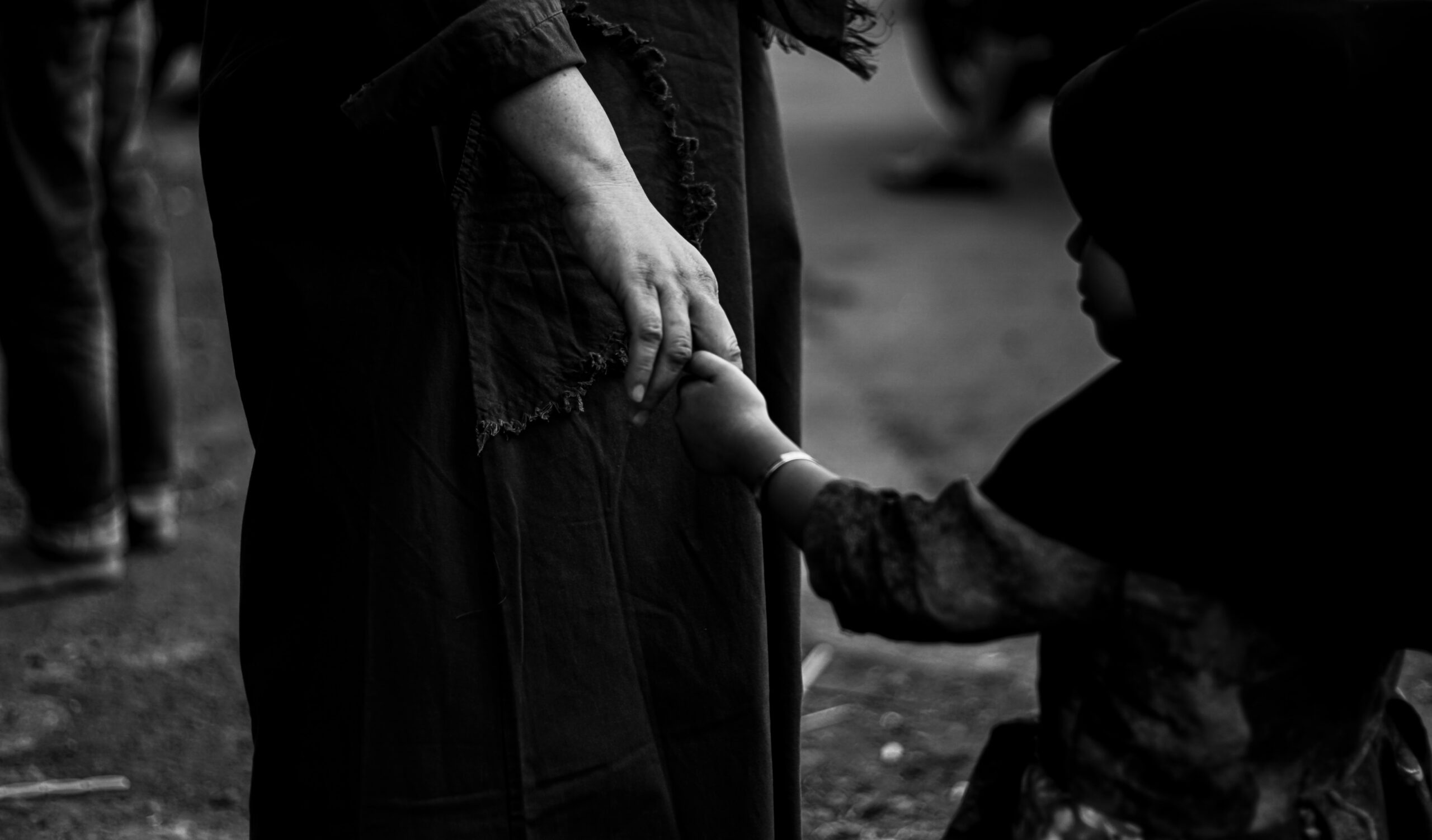Child holding the hand of a women in black and white