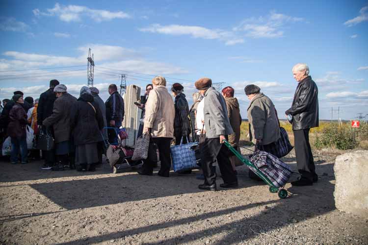 Refugees queuing along a road in coats with bags