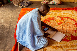A kneeling man checks a book.