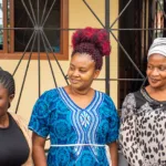 Three women stand outside the TCDWC office