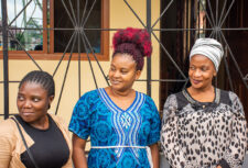 Three women stand outside the TCDWC office