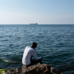 A person sits by the ocean. Credit Jonathon Moore Photography