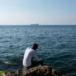 A person sits by the ocean. Credit Jonathon Moore Photography