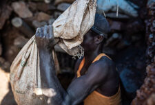 A gold miner carries earth from a mine in eastern Luhihi, DRC
