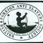 Logo of the British and Foreign Anti-Slavery Society. In the centre a kneeling man raises his shackled hands. The inlaid motto reads am I not a man and a brother.