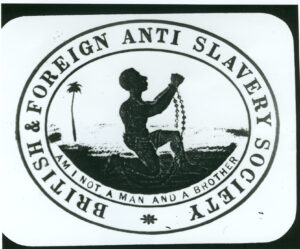Logo of the British and Foreign Anti-Slavery Society. In the centre a kneeling man raises his shackled hands. The inlaid motto reads am I not a man and a brother.