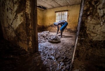 A man cleans mud from his flooded home