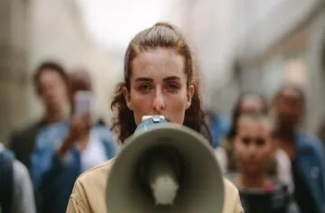 A woman at the front of a crowd speaks into a megaphone