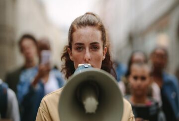A woman at the front of a crowd speaks into a megaphone