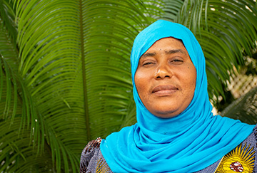 A woman stands in front of a palm tree