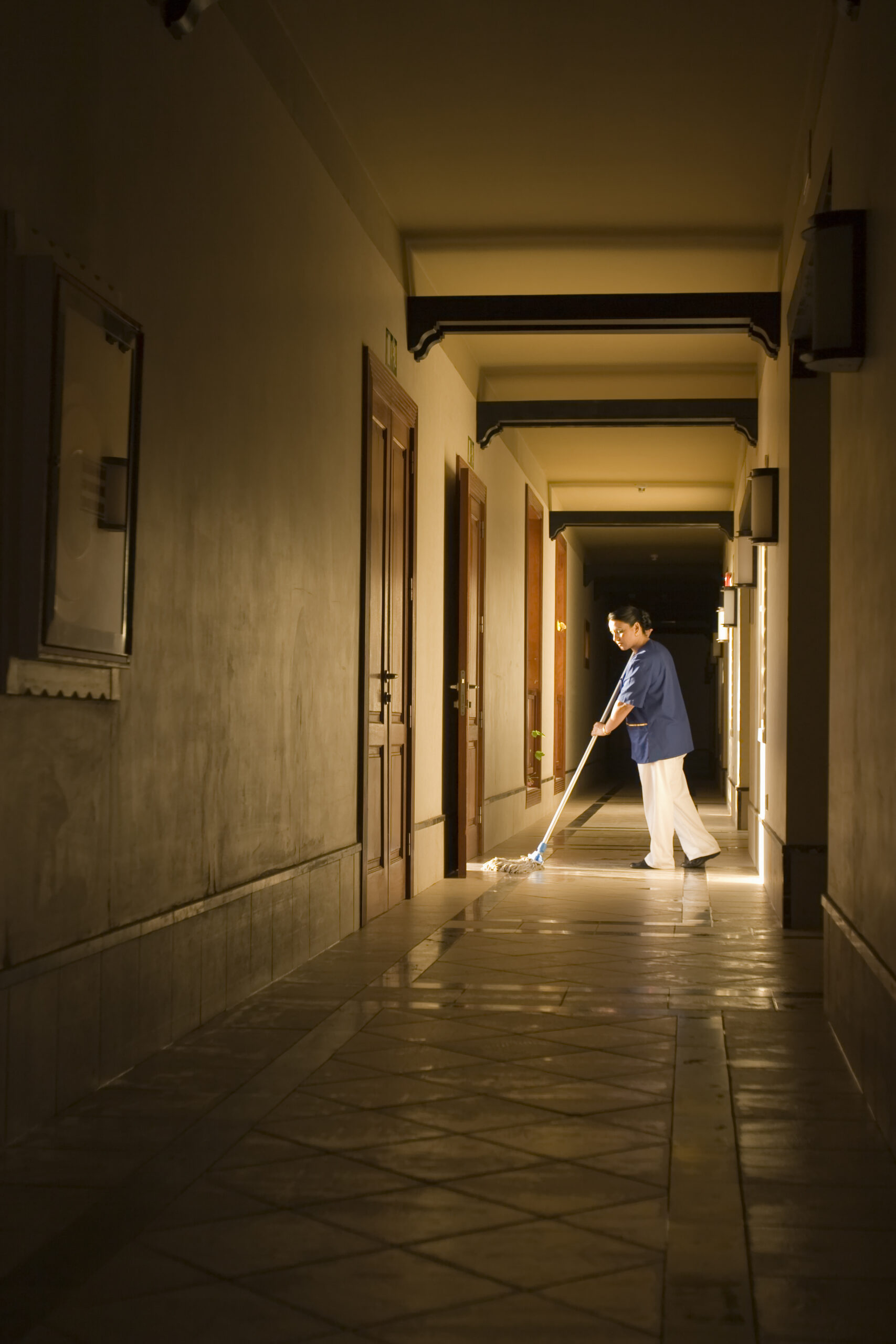 Maid at work mopping a tile floor.