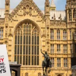Sign with Anti-Slavery International's logo being held outside the Houses of Parliament, UK