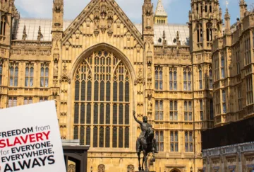 Sign with Anti-Slavery International's logo being held outside the Houses of Parliament, UK