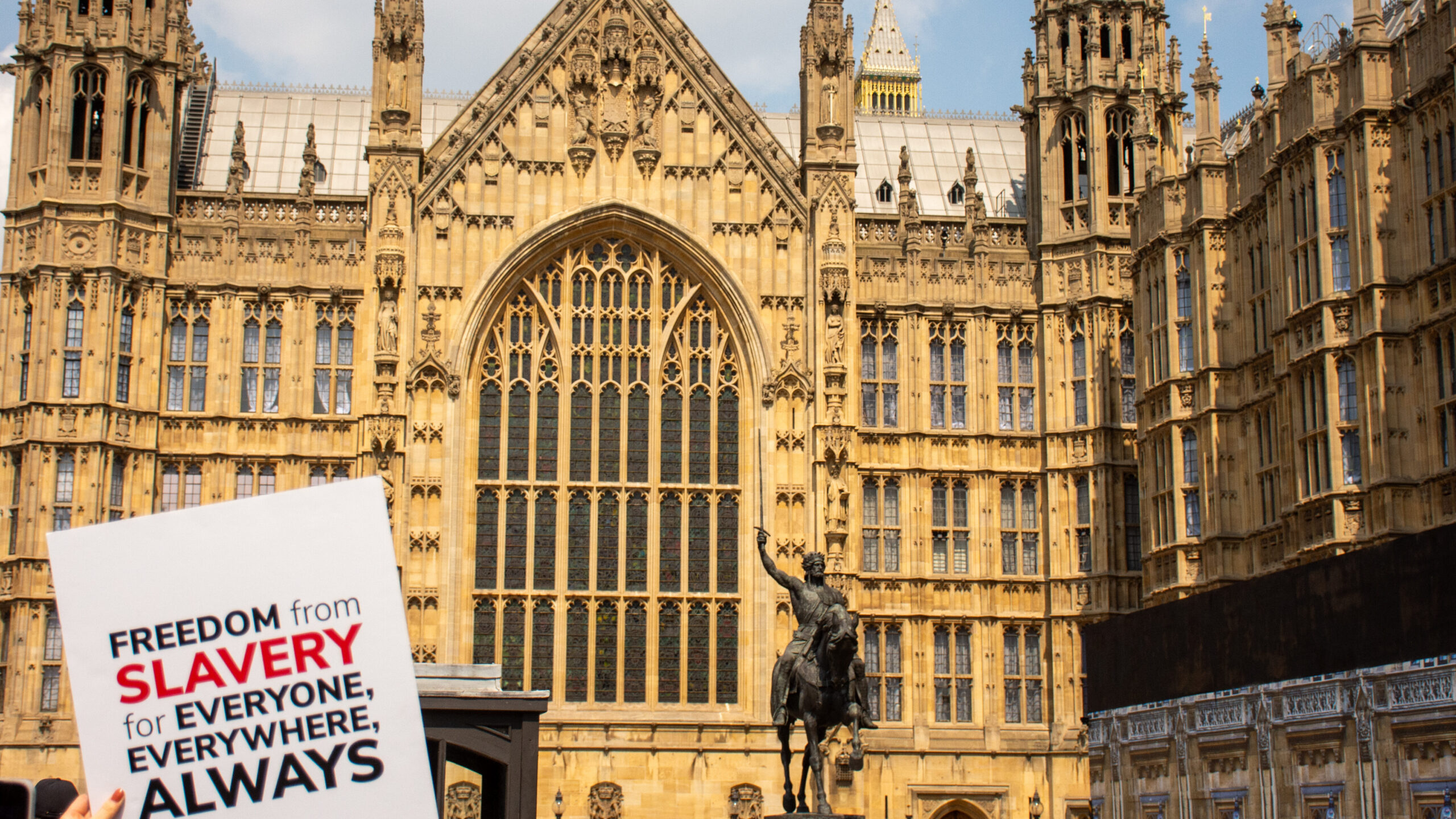 Sign with Anti-Slavery International's logo being held outside the Houses of Parliament, UK