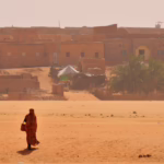 Woman in a dry riverbed, Wadi or Oued, in front of the historic centre, Chinguetti, Adrar Region, Mauritania