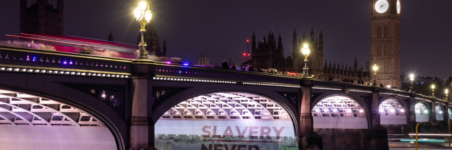 A projection on Westminster Bridge that reads "Slavery Never Ended"